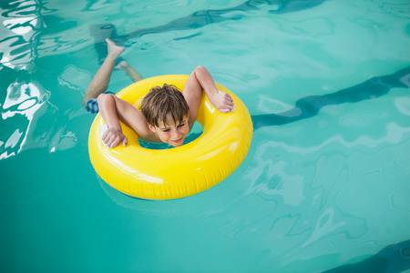 Little boy swimming with rubber ring at the leisure centerの写真素材