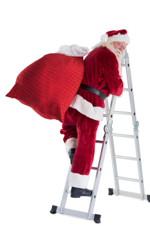 Santa steps up a ladder on white background and looks backの写真素材