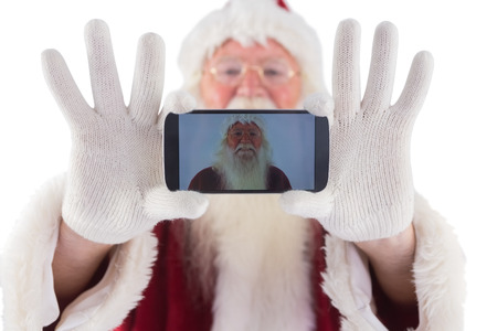 Santa records himself with a smartphone on white backgroundの写真素材