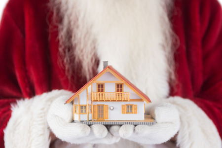 Santa holds a tiny house in his hands on white backgroundの写真素材