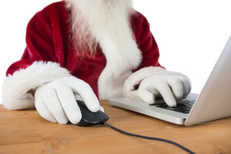 Santa surfs on the internet at a desk on white backgroundの写真素材