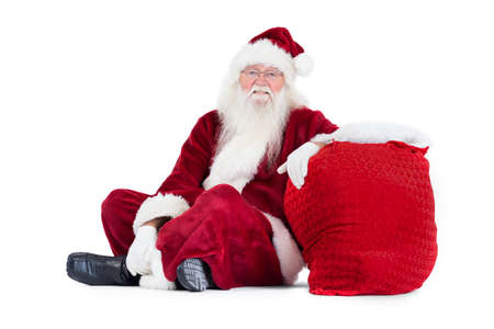 Santa sits next to his bag on white backgroundの写真素材