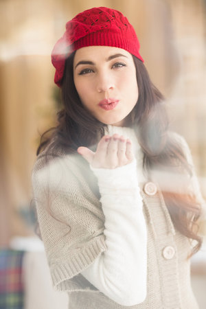 Pretty brunette blowing a kiss at home in the living roomの写真素材