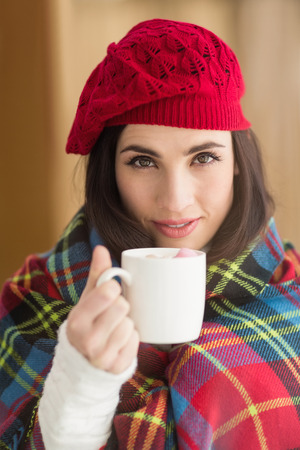 Brunette with cover holding mug at home in the living roomの写真素材