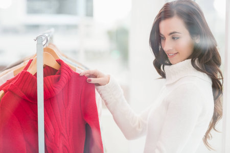 Pretty brunette looking at clothes on rail at clothes storeの写真素材