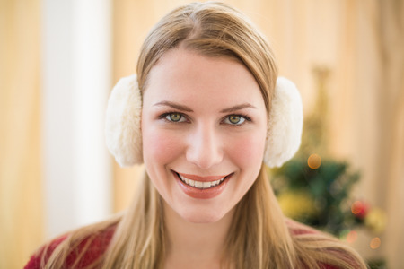 Portrait of a smiling blonde wearing earmuffs at home in the living roomの写真素材