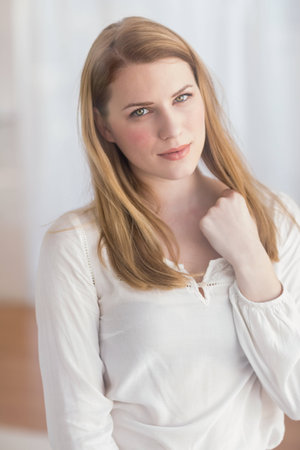 Woman celebrating success with her hand at home in the living roomの写真素材