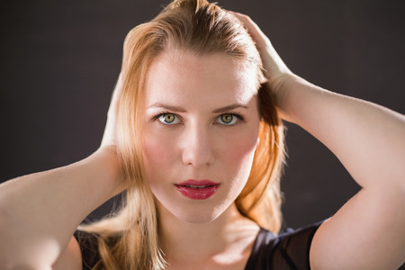 Pretty blonde model in black dress posing hands in the hair on black backgroundの写真素材