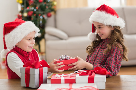 Festive siblings smiling at their gifts at home in the living roomの写真素材