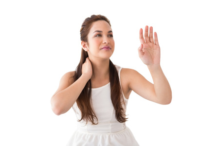 Thoughtful brunette with hand out on white backgroundの写真素材
