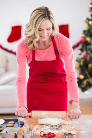Festive blonde making christmas cookies at home at christmasの写真素材