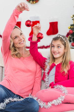 Festive mother and daughter smiling at camera  at home in the living roomの写真素材