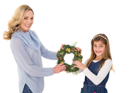 Festive mother and daughter holding christmas wreath on white backgroundの写真素材