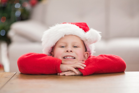 Festive little boy smiling at camera at home in the living roomの写真素材