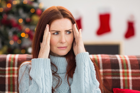 Woman getting a head ache at christmas at home in the living roomの写真素材