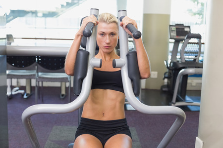 Portrait of a fit young woman using fitness machine at the gym