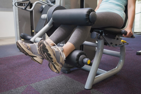 Fit woman using weights machine for legs at the gym