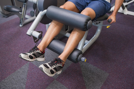 Fit man using weights machine for legs at the gym