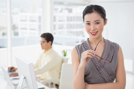 Pretty businesswoman smiling at camera in creative officeの写真素材