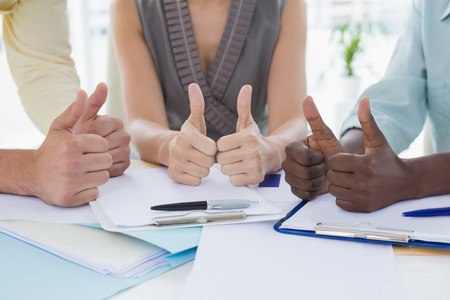 Business team showing thumbs up in creative officeの写真素材