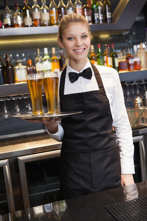 Pretty waitress holding a tray of champagne in a barの写真素材