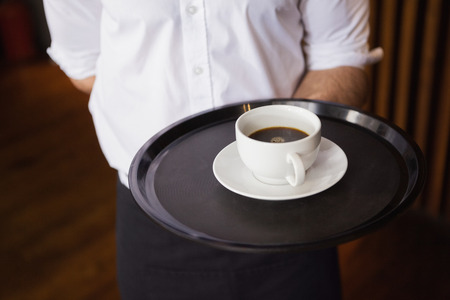 Waiter holding tray with coffee cup in a barの写真素材