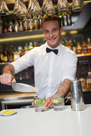 Happy bartender making a cocktail in a barの写真素材