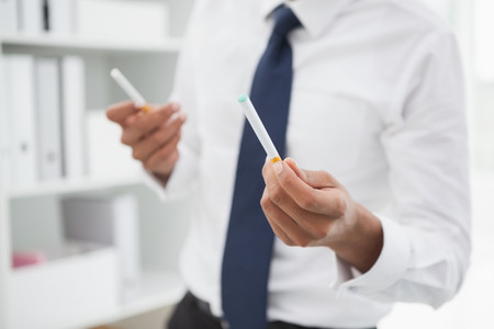 Mid section of a businessman holding cigarettes in his officeの写真素材