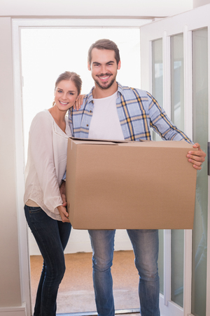 Cute couple carrying cardboard box in their new homeの写真素材