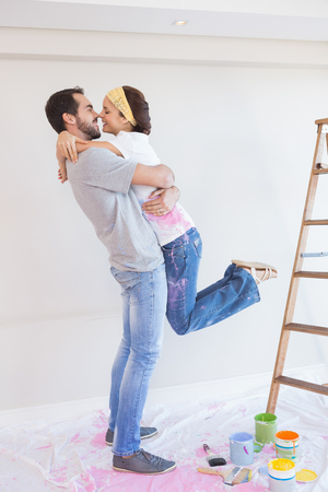 Cute couple hugging while redecorating in their new homeの写真素材