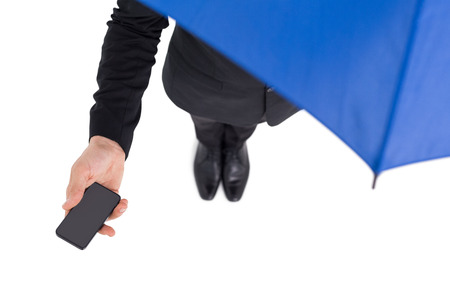 Businessman under umbrella holding mobile phone on white backgroundの写真素材