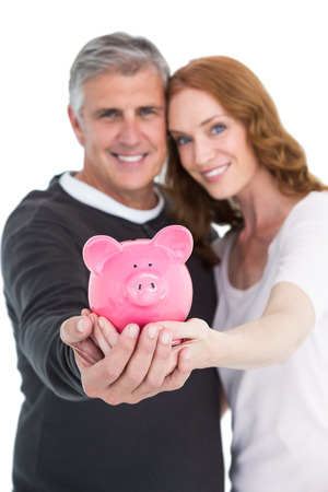 Casual couple showing their piggy bank on white backgroundの写真素材