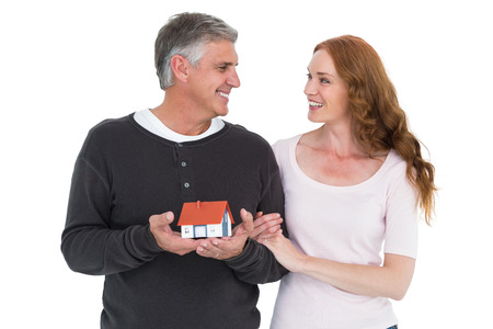 Casual couple holding small house on white backgroundの写真素材