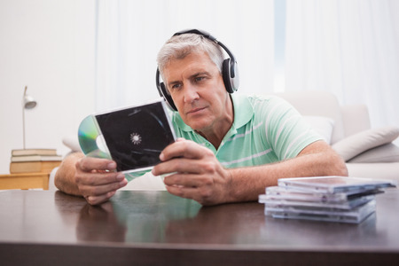 Mature man listening to cds at home in the living roomの写真素材
