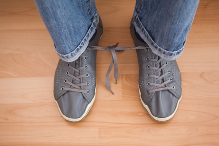 Casual mans shoelaces tied together at home in the living room