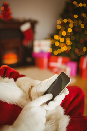 Santa claus using a smartphone at christmas at home in the living roomの写真素材