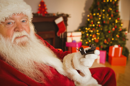 Father christmas holding engagement ring with his box at home in the living roomの写真素材