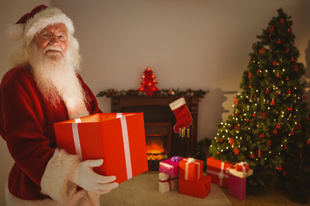 Happy santa delivering presents at christmas eve at home in the living roomの写真素材