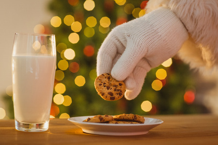 Hand of santa claus picking cookie on the table at homeの写真素材