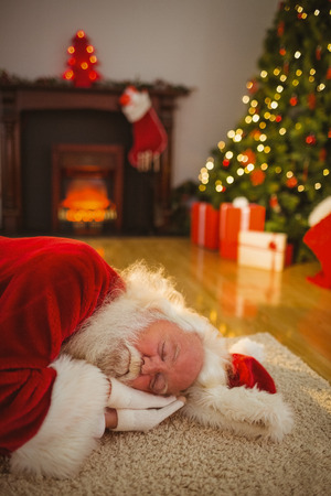 Santa claus napping on the rug at home in the living roomの写真素材