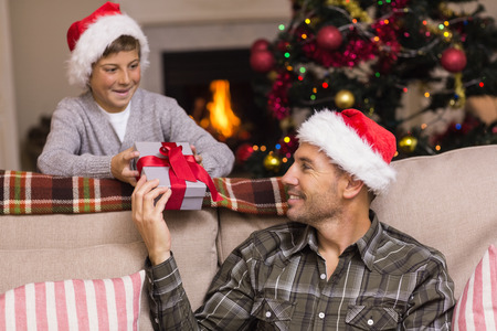 Father giving his son a christmas present at home in the living roomの写真素材