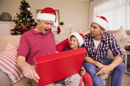 Surprised grandfather opening his gift at home in the living roomの写真素材