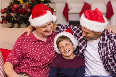 Portrait of grandfather father and son in santa hats at home in the living room