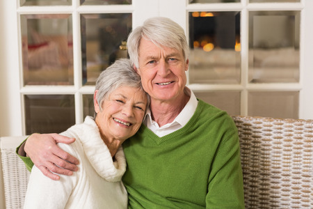 Portrait of smiling mature couple at table at home in the living room