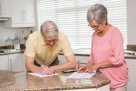 Senior couple paying their bills at home in the kitchenの写真素材