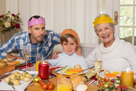 Portrait of grandmother father and son in party hat at home in the living roomの写真素材