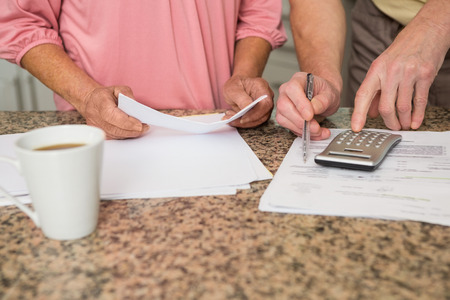Senior couple paying their bills at home in the kitchenの写真素材
