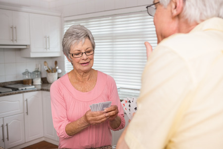 Senior couple playing cards at the counter at home in the kitchenの写真素材