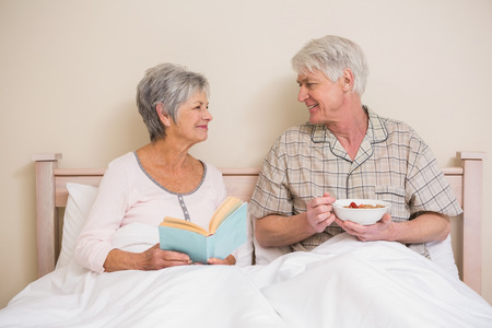 Senior couple relaxing in bed at home in bedroomの写真素材