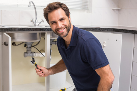 Plumber fixing under the sink in the kitchen